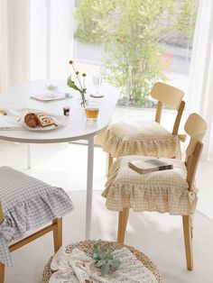 a table with two chairs and a basket on the floor in front of a window