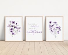 three purple flowers are on the wall next to two framed art prints that say, in a field of roses there is a wildflower