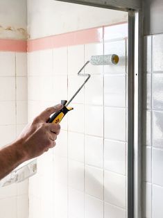 a man holding a wrench in his hand while he is working on a shower