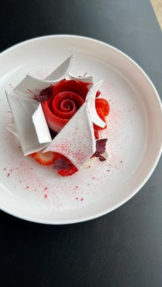 a white plate topped with a piece of cake covered in icing and strawberries