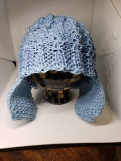 a blue knitted hat sitting on top of a white box next to a wooden table