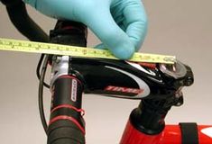 a person in blue gloves is measuring the handlebars on a red and black bike