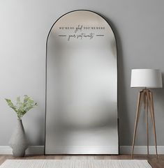 a large mirror sitting on top of a wooden floor next to a lamp and vase