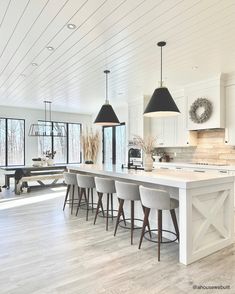 an instagramted photo of a kitchen with white cabinets and bar stools in the center