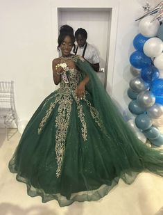 a woman in a green ball gown standing next to balloons