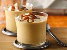 two glasses filled with dessert sitting on top of a wooden table