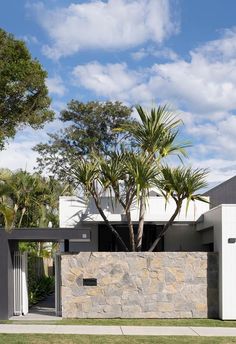 a modern house with stone walls and palm trees