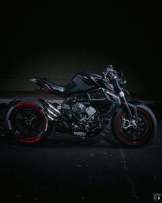 a motorcycle parked in the dark with red rims