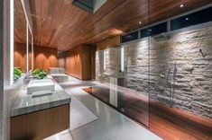 a bathroom with stone walls and wood ceilinging, along with a glass enclosed shower area