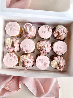 pink cupcakes with white frosting in a box on top of a table