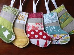 five oven mitts are lined up on a wooden table with white ribbons hanging from them