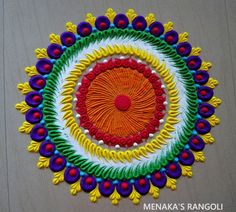 a colorful circular design made with beads and threads on a wooden table top in the shape of a sun