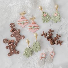 christmas ornaments are arranged on a white lace tablecloth, including gingerbreads and reindeer ornament