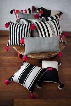 black and white striped pillows with pom poms on the bottom, along with pink tassels