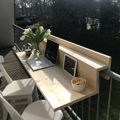 a laptop computer sitting on top of a wooden table next to a bowl of fruit