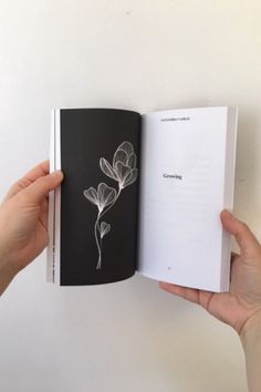 a person holding an open book with flowers on it