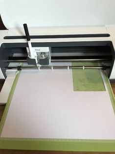 a machine that is cutting paper on top of a piece of paper next to a printer