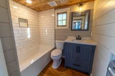 a white toilet sitting next to a bath tub in a bathroom under a wooden ceiling