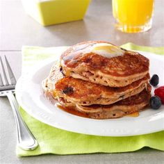 a stack of pancakes on a plate with syrup and berries