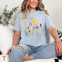 Wear nature's beauty with our Pressed Flowers T-shirt 🌼🦋. Adorned with delicate pressed flowers, butterflies, and a single ladybug, this tee combines elegance and charm. Experience comfort and style with this unique floral design. 🌸🐞 📍Also avail. as a tank top- https://ruthlessgifts.etsy.com/listing/1661530589 📍& avail. as a sweatshirt- https://ruthlessgifts.etsy.com/listing/1647352330 How to order? 🧐 ✓Review all images in this listing for style, color, and sizes. ✓Select the size and color of the Item from the drop-down menus. ✓Add to cart 🔥 UNISEX 🔥 ✓ Light fabric  ✓ Retail fit ✓ Tear-away label ✓ Runs true to size 📌 The available colors are what we feel would go best with each particular design. A full color chart is shown in the above pictures-- if you would like a design in Casual Spring Tops With Birth Flower Design, Spring Birth Flower Crew Neck T-shirt, Spring Birth Flower Short Sleeve T-shirt, Butterfly Tshirt, Unique Floral Design, Boho Nature, Cottagecore Shirt, Floral Cottagecore, Flowers Butterfly