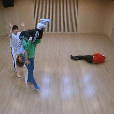 three people standing in an empty room with one laying on the floor and another lying down