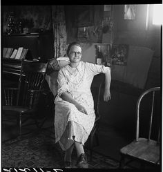 an old photo of a woman sitting in a chair with her arm around the neck