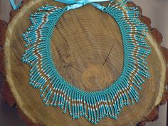 a blue and white beaded necklace sitting on top of a piece of tree trunk