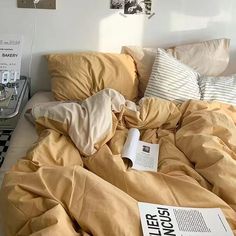 an unmade bed with yellow sheets and pillows on it, next to a black and white checkered floor