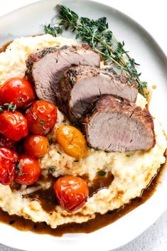 a plate with meat, mashed potatoes and cherry tomatoes