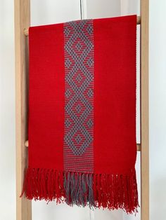 a red and grey blanket hanging from a wooden ladder