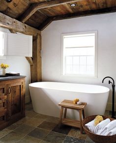 a white bath tub sitting under a window next to a wooden cabinet and counter top