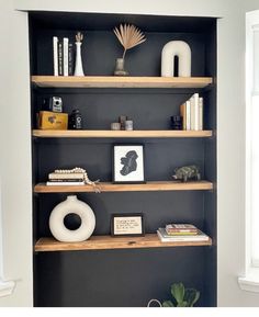 a book shelf filled with books and other items on top of wooden shelves next to a window