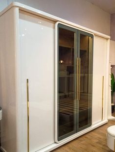 a large white cabinet with glass doors and gold handles in the middle of a room