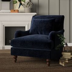 a blue chair sitting in front of a fireplace with books on the floor next to it