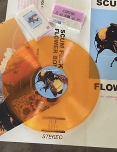 an orange and yellow colored record sitting on top of a piece of paper next to other records