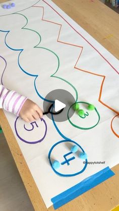 a young child is painting on a large piece of paper with numbers and shapes in it