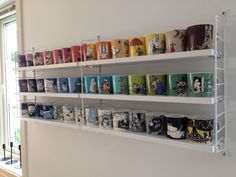 several rows of mugs are lined up on the wall