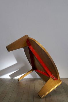 a wooden chair with a red ribbon on it's back and seat in the middle