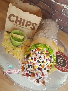 a burrito and chips on a clear plate