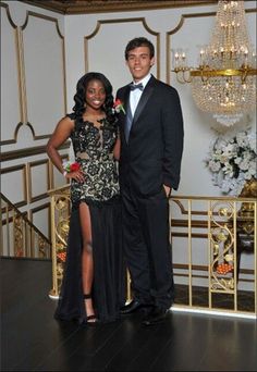 a man and woman standing next to each other in front of a chandelier