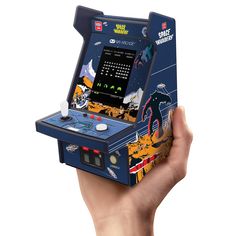 a hand holding up an old school arcade game system in front of a white background