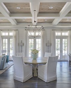 a large dining room with white chairs and a chandelier