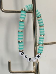 a blue and white beaded bracelet with the word ocean on it hanging from a hook