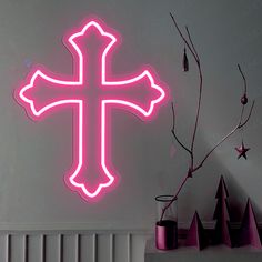 a pink neon cross on the wall next to a radiator