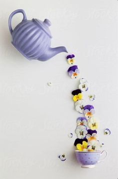 pansies falling out of a teapot into a bowl