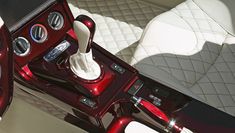 the interior of a luxury car with red and white trims, steering wheel and center console