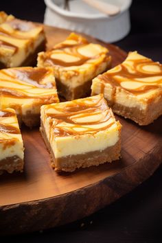 several pieces of cheesecake sitting on top of a wooden cutting board with caramel swirl toppings