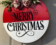 a merry christmas sign hanging from the side of a door with holly and bells on it