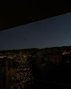 the city lights are lit up at night from an apartment building in this view looking out over town