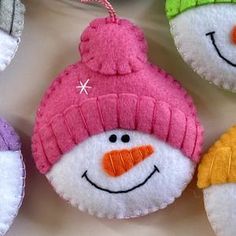 four snowman ornaments hanging from strings on a table